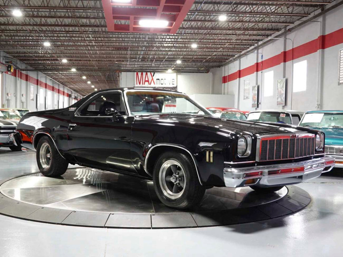 Restored black 1976 GMC Sprint displayed in an indoor showroom with chrome bumper and factory-style grille