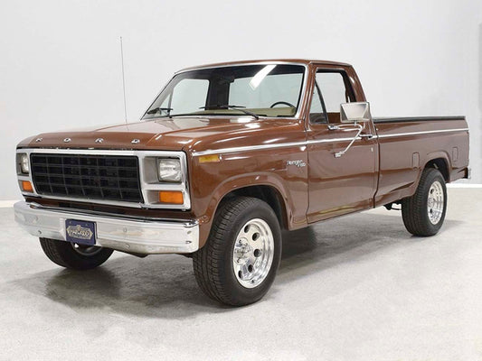 Restored brown 1981 Ford F-150 Ranger pickup parked indoors with chrome wheels and original grille