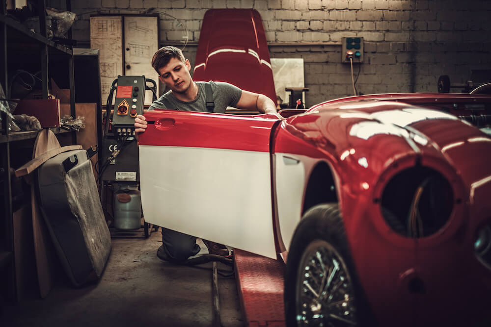 Man studying door of classic car in garage
