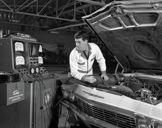 Vintage photo of mechanic working on classic car using old equipment