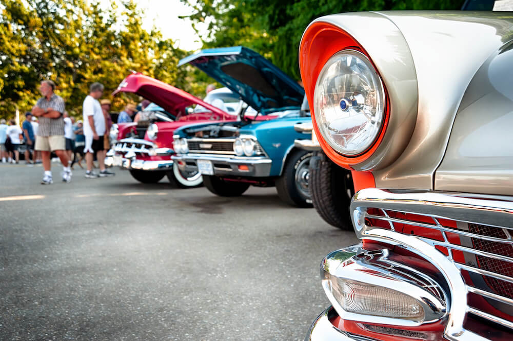 Vintage cars in a parking lot with people perusing